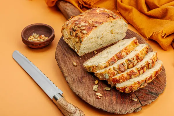 Balkabağı tohumlu taze ekmek. Ev yapımı konsept. Sonbahar dekoru, balkabağım, sonbahar yaprakları. Tahta kesme tahtası, pastel bej arkaplan, kopyalama alanı