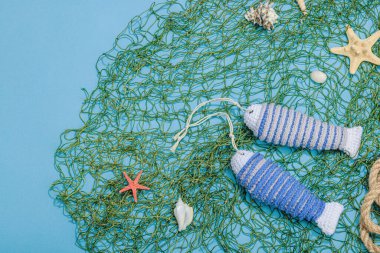 El yapımı denizci konsepti. Tığ işi sardalya balıkları, deniz usulü. Balık ağı, geleneksel deniz dekoru. Sert ışık, koyu gölge, modaya uygun mavi arkaplan, üst görünüm