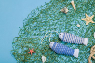 El yapımı denizci konsepti. Tığ işi sardalya balıkları, deniz usulü. Balık ağı, geleneksel deniz dekoru. Sert ışık, koyu gölge, modaya uygun mavi arkaplan, üst görünüm