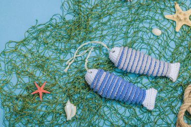 El yapımı denizci konsepti. Tığ işi sardalya balıkları, deniz usulü. Balık ağı, geleneksel deniz dekoru. Sert ışık, koyu gölge, modaya uygun mavi arkaplan, üst görünüm