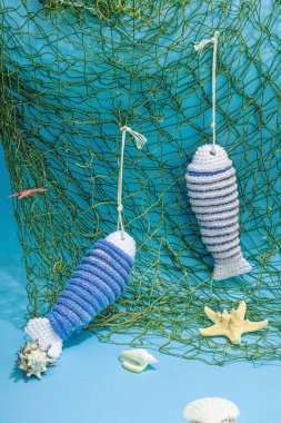 El yapımı denizci konsepti. Tığ işi sardalya balıkları, deniz usulü. Balık ağı, geleneksel deniz dekoru. Sert ışık, koyu gölge, modaya uygun mavi arkaplan, kopyalama alanı