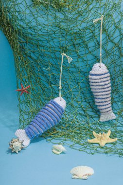 El yapımı denizci konsepti. Tığ işi sardalya balıkları, deniz usulü. Balık ağı, geleneksel deniz dekoru. Sert ışık, koyu gölge, modaya uygun mavi arkaplan, kopyalama alanı