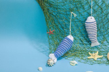 El yapımı denizci konsepti. Tığ işi sardalya balıkları, deniz usulü. Balık ağı, geleneksel deniz dekoru. Sert ışık, koyu gölge, modaya uygun mavi arkaplan, kopyalama alanı