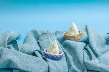 El yapımı denizci konsepti. Tığ işi tekneler, denizcilik tarzı, geleneksel deniz dekoru. Sert ışık, koyu gölge, modaya uygun mavi arkaplan, kopyalama alanı