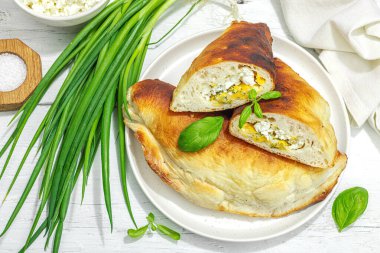 Süzme peynirli ve yeşillikli ev yapımı börek turtaları. Yüksek proteinli yiyecekler, glütensiz fırın. Modaya uygun sert ışık, koyu gölge, beyaz ahşap zemin, üst manzara