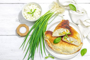 Süzme peynirli ve yeşillikli ev yapımı börek turtaları. Yüksek proteinli yiyecekler, glütensiz fırın. Modaya uygun sert ışık, koyu gölge, beyaz ahşap zemin, üst manzara