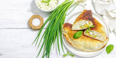 Süzme peynirli ve yeşillikli ev yapımı börek turtaları. Yüksek proteinli yiyecekler, glütensiz fırın. Modaya uygun sert ışık, koyu gölge, beyaz ahşap arkaplan, afiş biçimi