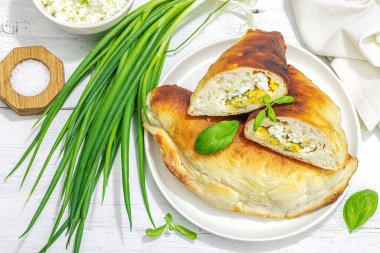 Süzme peynirli ve yeşillikli ev yapımı börek turtaları. Yüksek proteinli yiyecekler, glütensiz fırın. Modaya uygun sert ışık, koyu gölge, beyaz ahşap zemin, üst manzara