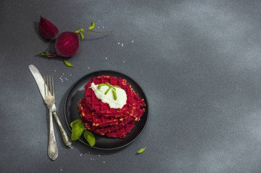 Ev yapımı Belçika usulü soslu pancar. Sebzeli glütensiz vegan yemeği. Modaya uygun sert ışık, koyu gölge, siyah taş beton zemin, üst görünüm