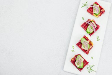 Lezzetli bir iştah açıcı. Baharatlı ve soslu pancar gözlemelerinin üzerinde ringa balığı var. Modaya uygun sert ışık, koyu gölge, taş beton zemin, üst görünüm