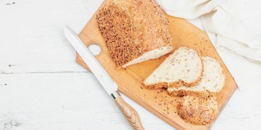 Çeşitli tohumlarla taze ekmek. Evde pişirme glütensiz konsept, hobi. Tahta kesme tahtası, beyaz arkaplan, pano biçimi