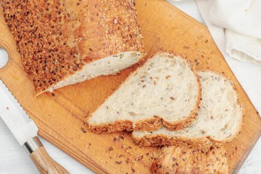 Çeşitli tohumlarla taze ekmek. Evde pişirme glütensiz konsept, hobi. Tahta kesim tahtası, beyaz arkaplan, üst manzara