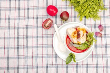 Domates çorbası çorbası hazır. Servis porsiyonu, çatal bıçak takımı. Masadaki kareli masa örtüsü, düz, üst görünüm