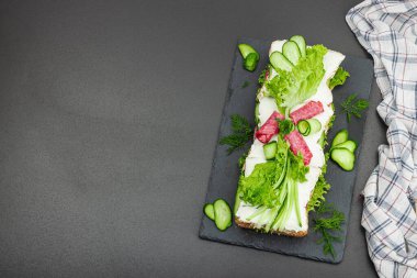 İsveç sandviçi Smorgastarta. Geleneksel soğuk aperatif servisi, yemeye hazır. Modern duruş, şenlikli yemek, siyah taş beton arka plan, üst görünüm