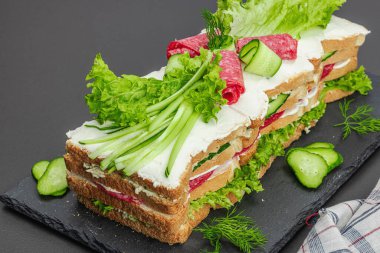 İsveç sandviçi Smorgastarta. Geleneksel soğuk aperatif servisi, yemeye hazır. Modern duruş, şenlikli yemek, siyah taş beton arka plan, yakın çekim.