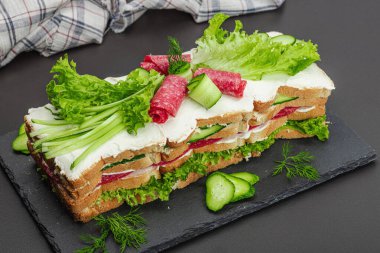 İsveç sandviçi Smorgastarta. Geleneksel soğuk aperatif servisi, yemeye hazır. Modern duruş, şenlikli yemek, siyah taş beton arka plan, yakın çekim.