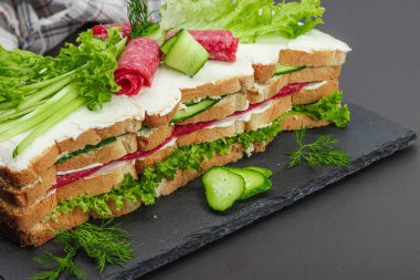 İsveç sandviçi Smorgastarta. Geleneksel soğuk aperatif servisi, yemeye hazır. Modern duruş, şenlikli yemek, siyah taş beton arka plan, yakın çekim.