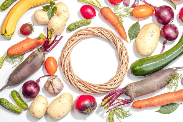 Harvest of autumn vegetables isolated on white background. Wicker wreath, hard light, dark shadow, flat lay, top view