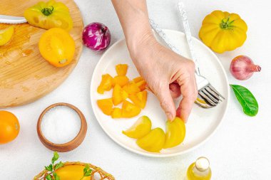 Bir kadın domates salatası hazırlıyor. Olgun sebzeler, bitkiler, aromatik baharatlar, zeytinyağı. Ev yemeği, taze malzemeler, üst manzara.