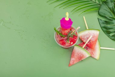 Karpuz kokteylini tazeliyorum. Geleneksel yaz içkisi. Moda Savannah yeşili arka plan, palmiye yaprakları, üst manzara