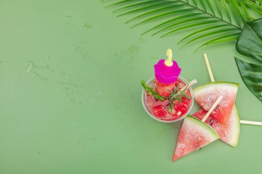 Karpuz kokteylini tazeliyorum. Geleneksel yaz içkisi. Moda Savannah yeşili arka plan, palmiye yaprakları, üst manzara