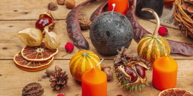 Sonbahar kompozisyonu. Sepette balkabakları, mumlar, koniler, tohumlar. Geleneksel sonbahar dekoru, mevsimsel iyi ruh hali. Düz konum, tahta arkaplan, pankart biçimi