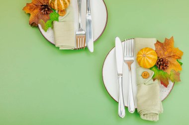 Sonbahar sofrası. Şükran Günü çatal bıçak takımı, geleneksel sonbahar dekorasyonu, düz yatış. Neşeli bir ortam, balkabağı, yapraklar, Savannah Green arka plan, üst manzara.
