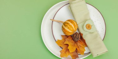 Sonbahar sofrası. Şükran Günü çatal bıçak takımı, geleneksel sonbahar dekorasyonu, düz yatış. Şenlik havası, balkabağı, yapraklar, Savannah Green arka planı, afiş biçimi