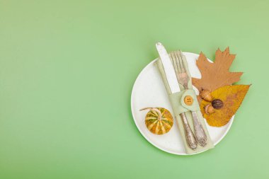 Sonbahar sofrası. Şükran Günü çatal bıçak takımı, geleneksel sonbahar dekorasyonu, düz yatış. Neşeli bir ortam, balkabağı, yapraklar, Savannah Green arka plan, üst manzara.