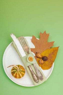 Sonbahar sofrası. Şükran Günü çatal bıçak takımı, geleneksel sonbahar dekorasyonu, düz yatış. Neşeli bir ortam, balkabağı, yapraklar, Savannah Green arka plan, üst manzara.