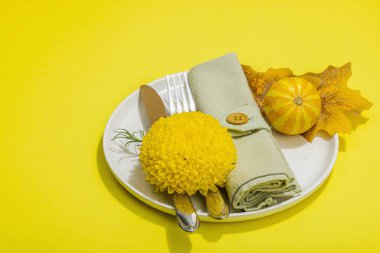 Sonbahar sofrası. Şükran Günü çatal bıçak takımı, geleneksel sonbahar dekorasyonu, düz yatış. Neşeli bir ortam, balkabağı, yapraklar, parlak sarı arka plan, kopyalama alanı