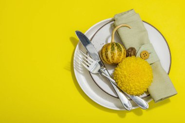 Sonbahar sofrası. Şükran Günü çatal bıçak takımı, geleneksel sonbahar dekorasyonu, düz yatış. Şen şakrak ruh hali, balkabağı, yapraklar, parlak sarı arka plan, üst manzara