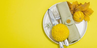 Sonbahar sofrası. Şükran Günü çatal bıçak takımı, geleneksel sonbahar dekorasyonu, düz yatış. Şenlik havası, balkabağı, yapraklar, parlak sarı arkaplan, afiş biçimi