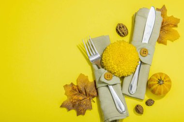 Sonbahar sofrası. Şükran Günü çatal bıçak takımı, geleneksel sonbahar dekorasyonu, düz yatış. Şen şakrak ruh hali, balkabağı, yapraklar, parlak sarı arka plan, üst manzara