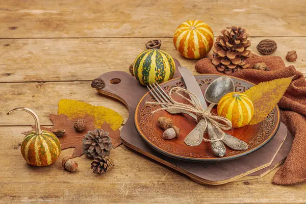 Autumn table setting. Thanksgiving cutlery, traditional fall decor, flat lay. Festive cozy mood, rustic style. Pumpkin, leaves, wooden background, copy space