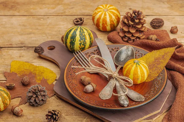 Autumn table setting. Thanksgiving cutlery, traditional fall decor, flat lay. Festive cozy mood, rustic style. Pumpkin, leaves, wooden background, copy space