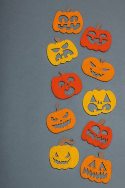 Komik cadılar bayramı geçmişi. Farklı yüzleri olan geleneksel renkli balkabakları. Şenlikli düz yatak, klasik sonbahar tarzı, üst görünüm