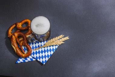 Geleneksel Ekim Festivali seti. Simitler ve bira, Alman festivali yemek konsepti. Modaya uygun sert ışık, koyu gölge, koyu taş beton zemin, üst manzara