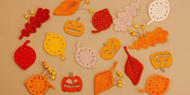 El yapımı sonbahar arkaplanı. Farklı düşme şekilleri, örülmüş yapraklar ve ahşap balkabakları. El işi, hobi konsepti, açık bej arkaplan üzerine geleneksel dekor, afiş biçimi