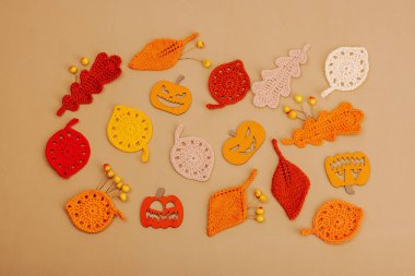 El yapımı sonbahar arkaplanı. Farklı düşme şekilleri, örülmüş yapraklar ve ahşap balkabakları. El işi, hobi konsepti, açık bej arka plan geleneksel dekor, üst görünüm