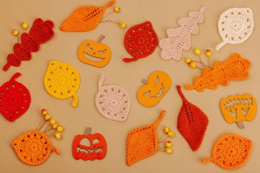 El yapımı sonbahar arkaplanı. Farklı düşme şekilleri, örülmüş yapraklar ve ahşap balkabakları. El işi, hobi konsepti, açık bej arka plan geleneksel dekor, üst görünüm