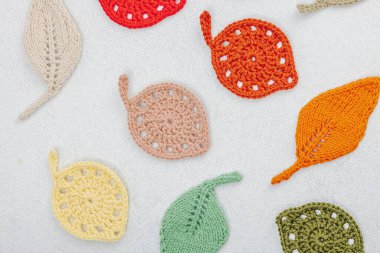 Örgü örmek için bir demet iplik. Tığ işi farklı yapraklar, el yapımı, sonbahar hobisi. Işık taşı arkaplan, üst görünüm üzerine dekorlar ve özel sanatlar araçları