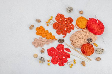 Örgü örmek için bir demet iplik. Tığ işi farklı yapraklar, el yapımı, sonbahar hobisi. Işık taşı arkaplan, üst görünüm üzerine dekorlar ve özel sanatlar araçları