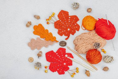 Örgü örmek için bir demet iplik. Tığ işi farklı yapraklar, el yapımı, sonbahar hobisi. Işık taşı arkaplan, üst görünüm üzerine dekorlar ve özel sanatlar araçları
