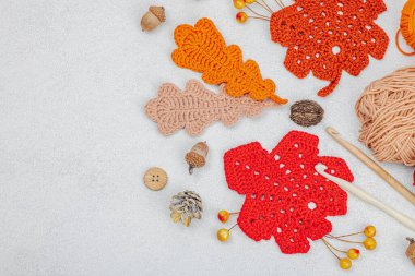 Örgü örmek için bir demet iplik. Tığ işi farklı yapraklar, el yapımı, sonbahar hobisi. Işık taşı arkaplan, üst görünüm üzerine dekorlar ve özel sanatlar araçları