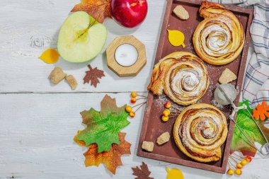Elma güllü turta ve şeker tozu. Geleneksel sonbahar pişirme, sonbahar dekorasyonu, düz yatak. Sert ışık, karanlık gölge, ahşap arka plan, üst manzara