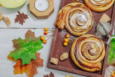 Elma güllü turta ve şeker tozu. Geleneksel sonbahar pişirme, sonbahar dekorasyonu, düz yatak. Sert ışık, karanlık gölge, ahşap arka plan, üst manzara