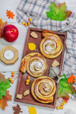 Elma güllü turta ve şeker tozu. Geleneksel sonbahar pişirme, sonbahar dekorasyonu, düz yatak. Sert ışık, karanlık gölge, ahşap arka plan, üst manzara