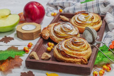 Elma güllü turta ve şeker tozu. Geleneksel sonbahar pişirme, sonbahar dekorasyonu, düz yatak. Sert ışık, karanlık gölge, ahşap arka plan, kapat