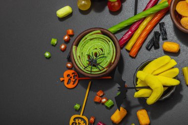 Cadılar Bayramı partisi için geleneksel festival kompozisyonu. Tatlı mevsimlik yemekler, ev yapımı sonbahar dekorasyonu. Sert ışık, karanlık gölge, siyah taş beton zemin, düz yatış, üst manzara